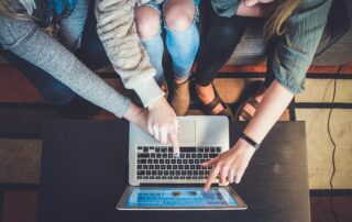 three person pointing the silver laptop computer